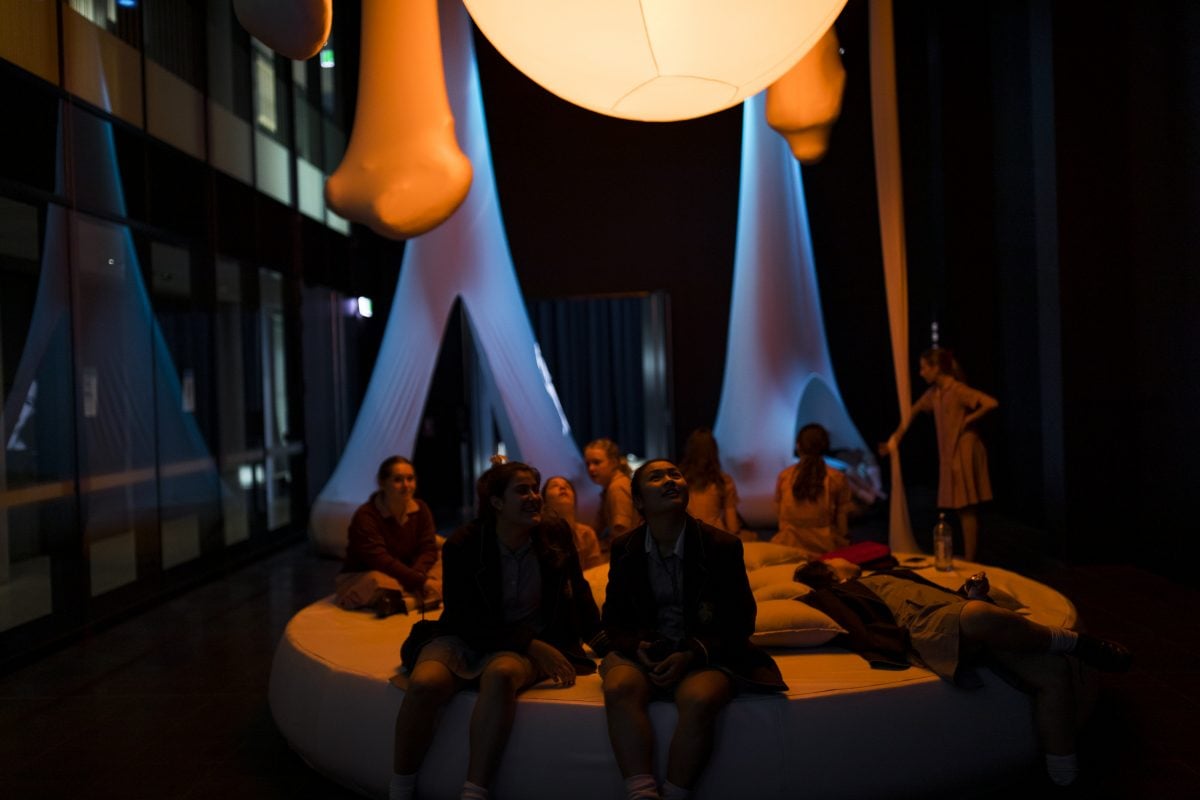 Young people sitting in a museum exhibit talking and laughing