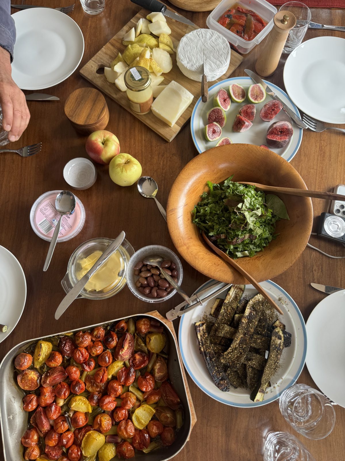 An overhead view of a table set for lunch with tomatoes, figs, zucchini and cheese.