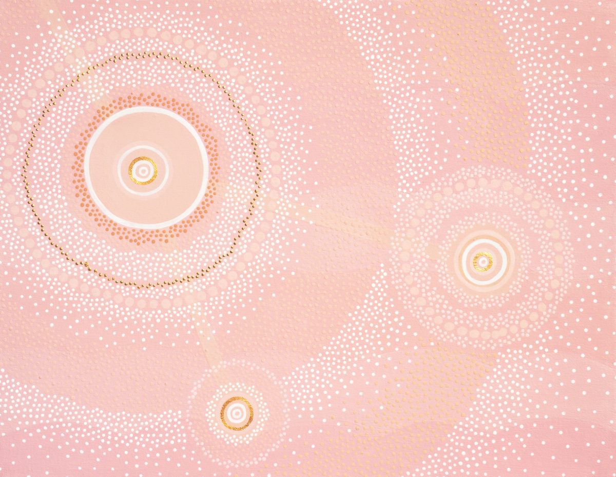 An acrylic artwork that consists of a soft, warm, light pink tonal background, overlaid with three solid pink circles varying in size. These three circles are linked together with three subtle peach coloured lines. Each circle is surrounded by a mass of white, pink & tan dots scattering in an outward motion. Integrated within these dots are hints of gold, forming circular patterns 