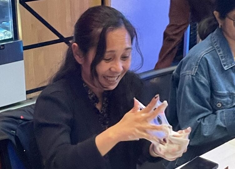 A person sitting at a table; they have slim between their hands