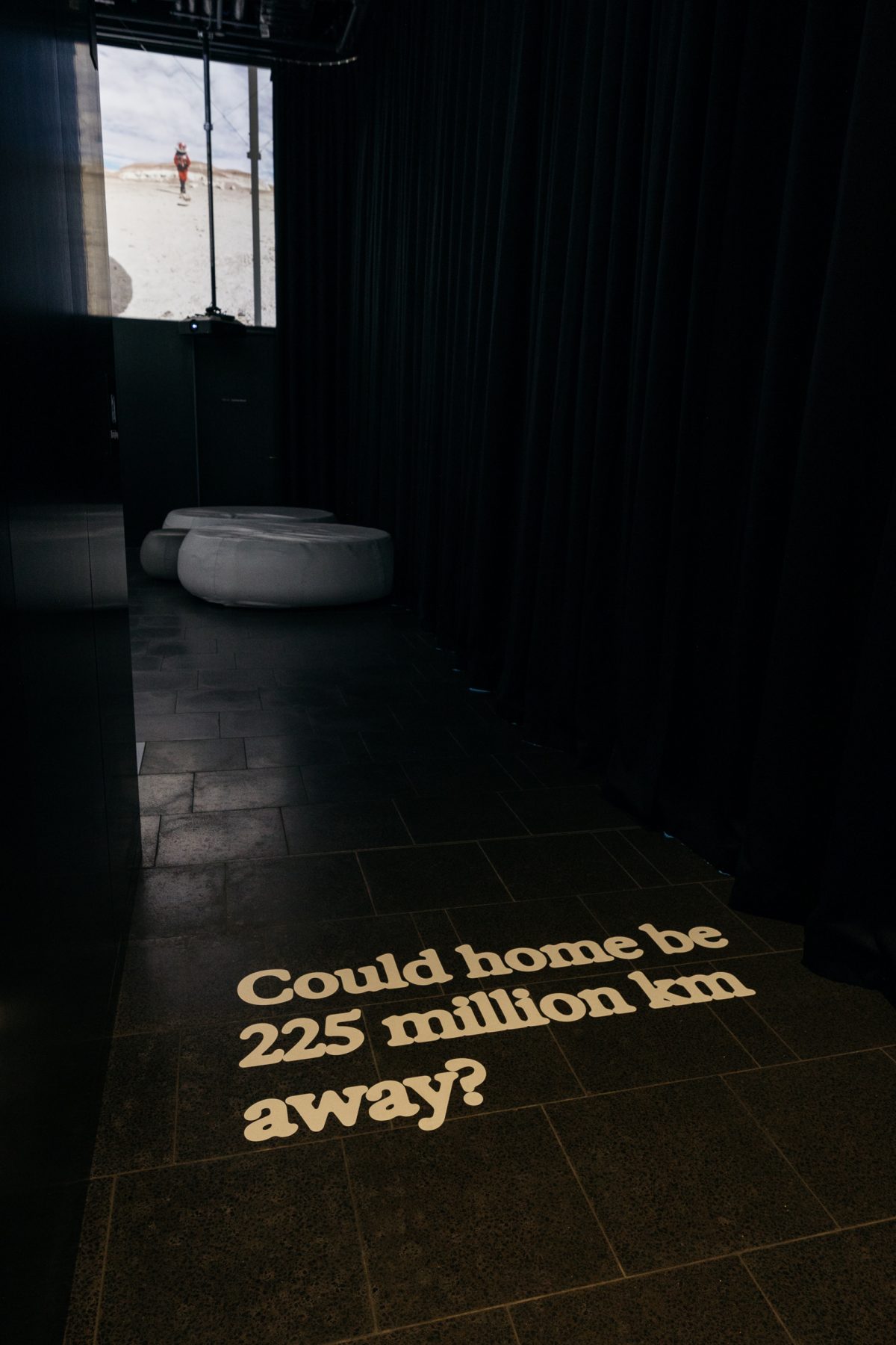 Text on floor of gallery reads 'Could home be 250million km away?'