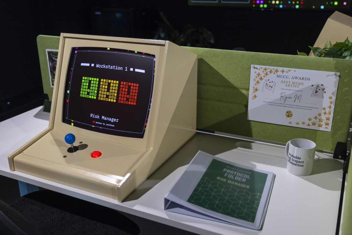 A retro looking computer with a game controls instead of a keyboard sits on a table for the 'risk manager' worker.