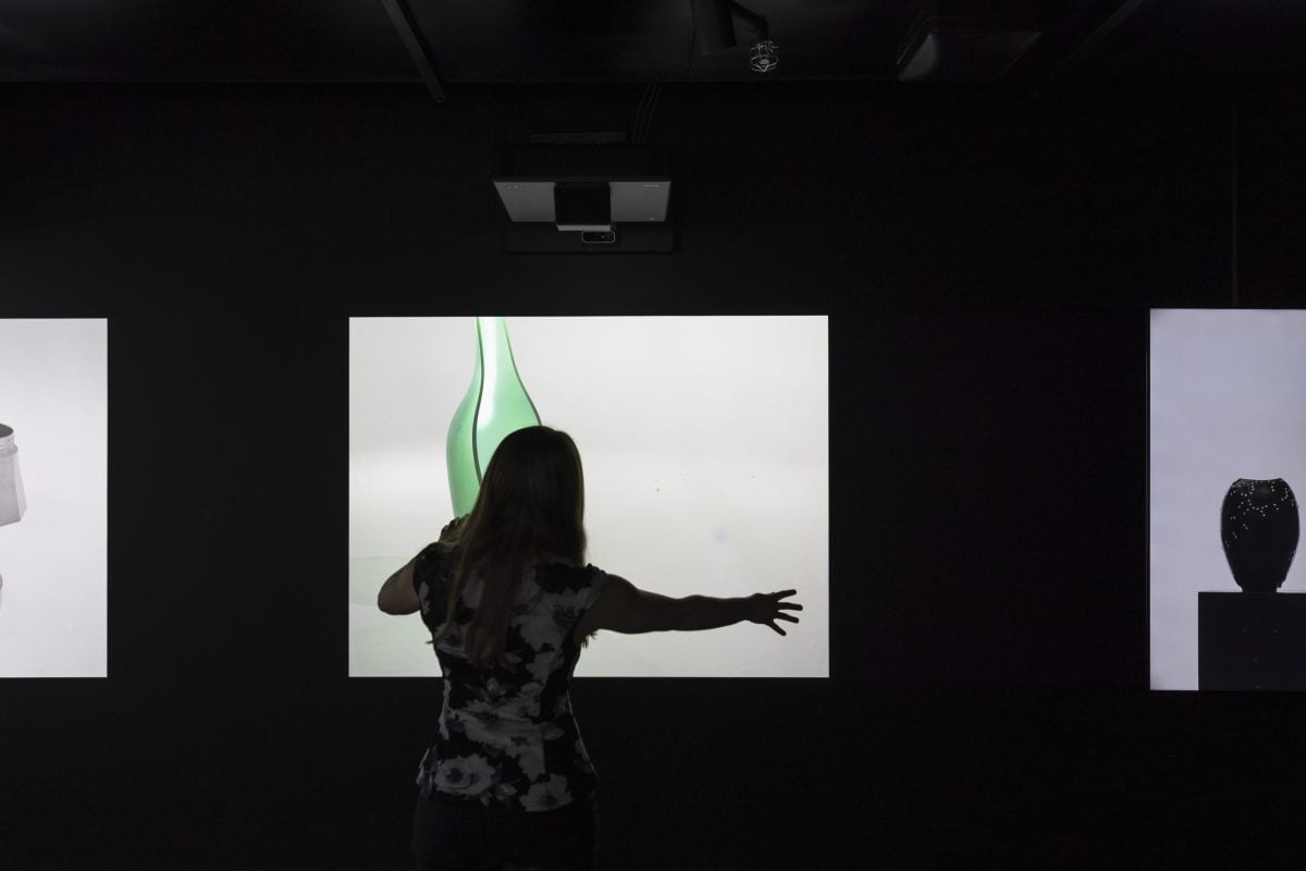 A silhouetted person stands in front of a screen with their arm outstretched.