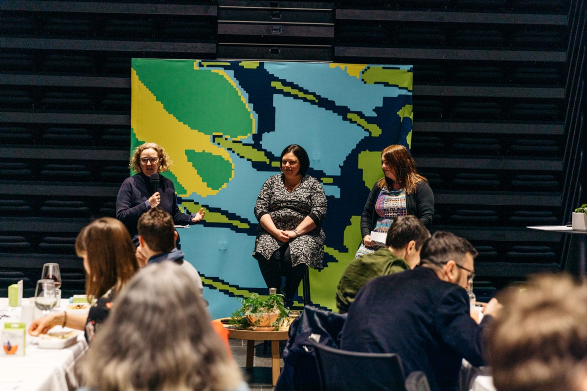 Three women seated on stools in panel discussion on the ethics of plant-based milks