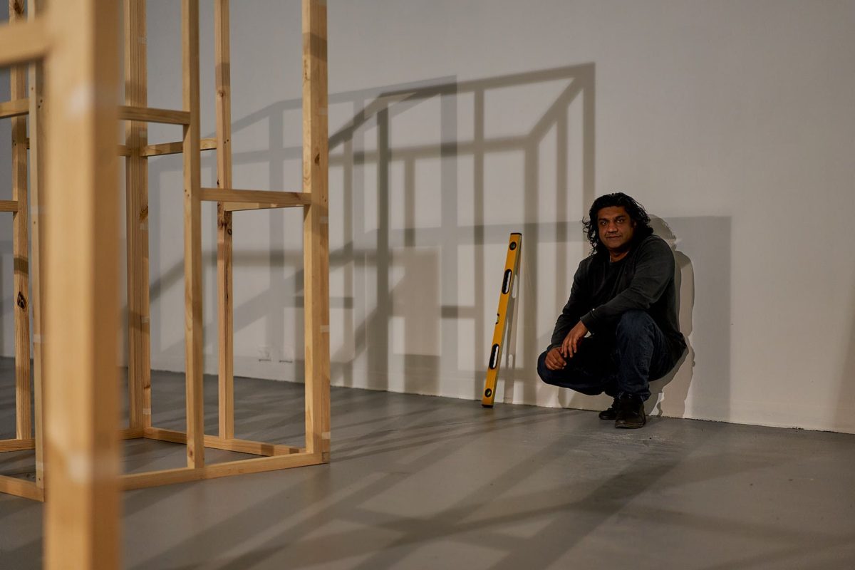 Yusuf Hayat crouching near a wooden structure